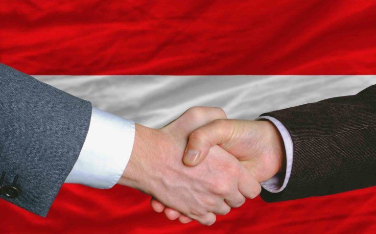 Unternehmer-Handschlag vor Österreich-Fahne